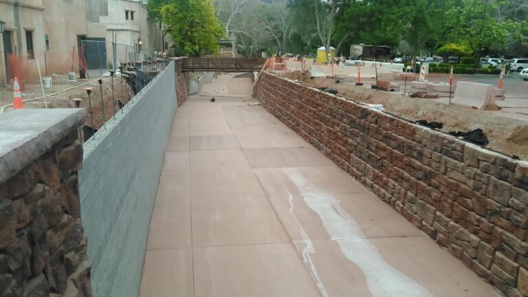 A nearly finished concrete drainage channel lined with bricks