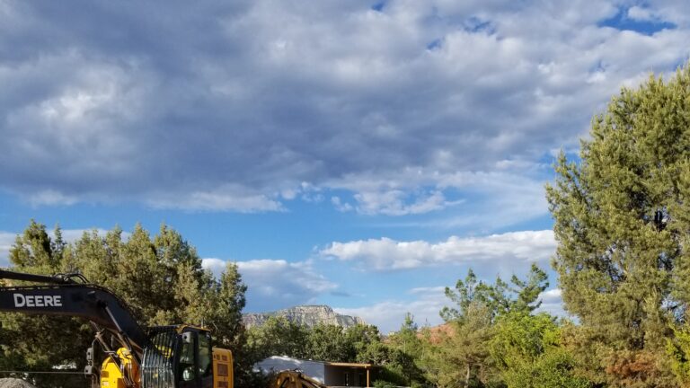A view of large drainage pipes in a trench with construction equipment in the bacckground