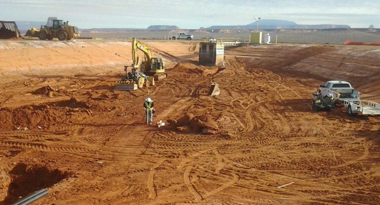 A worker surveying in a large hole