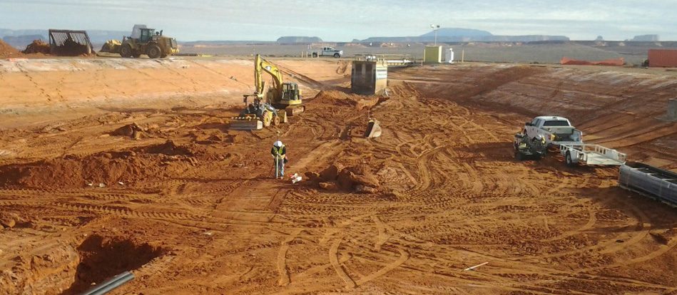 A worker surveying in a large hole