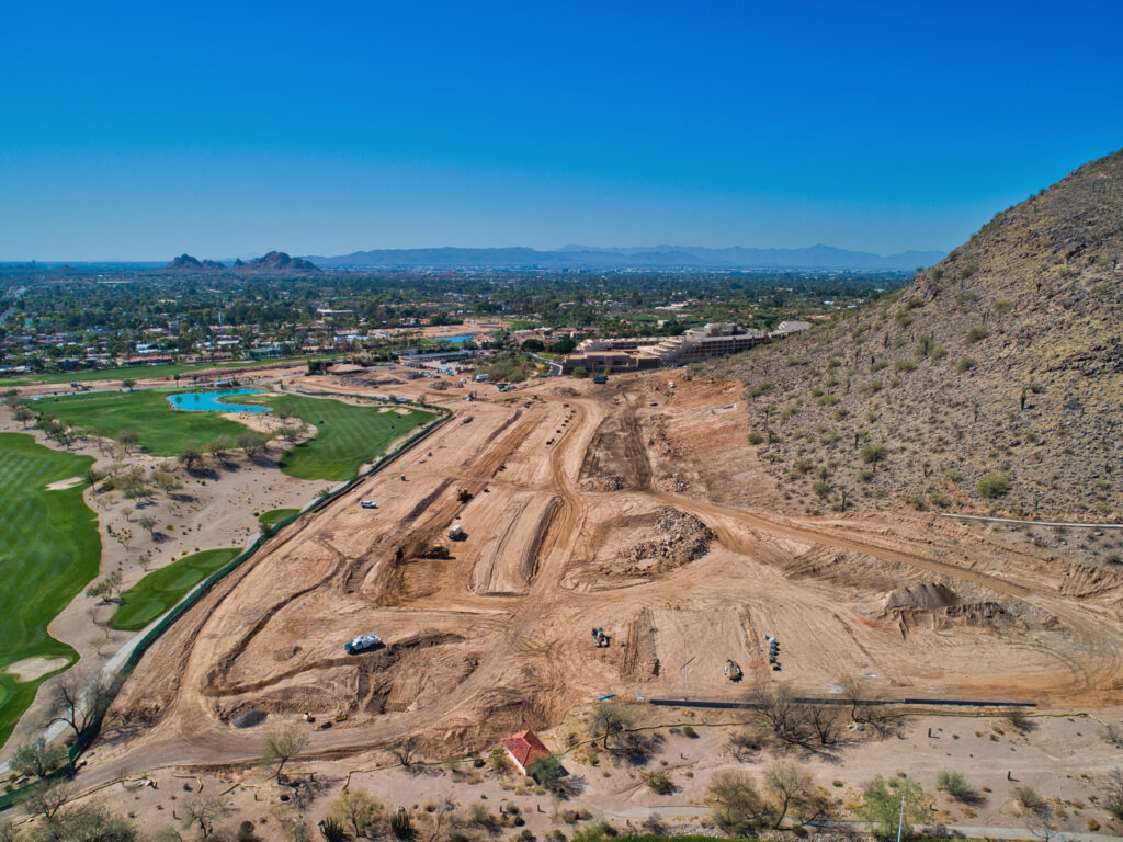 Aerial view of a subdivision being cleared and graded between a golf course and a mountain