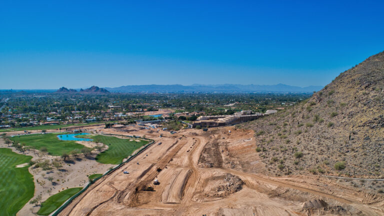 Aerial view of a subdivision being cleared and graded between a golf course and a mountain