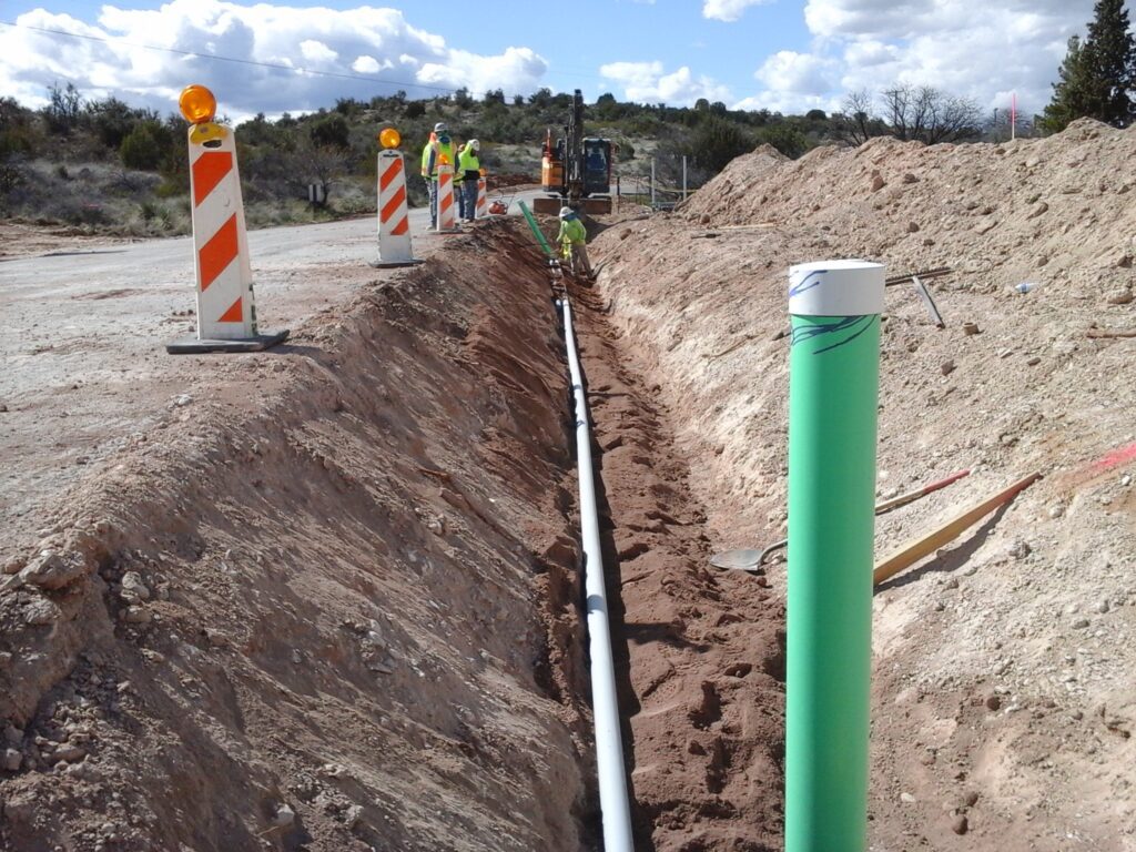 Construction workers with a backhoe digging a ditch for a water main