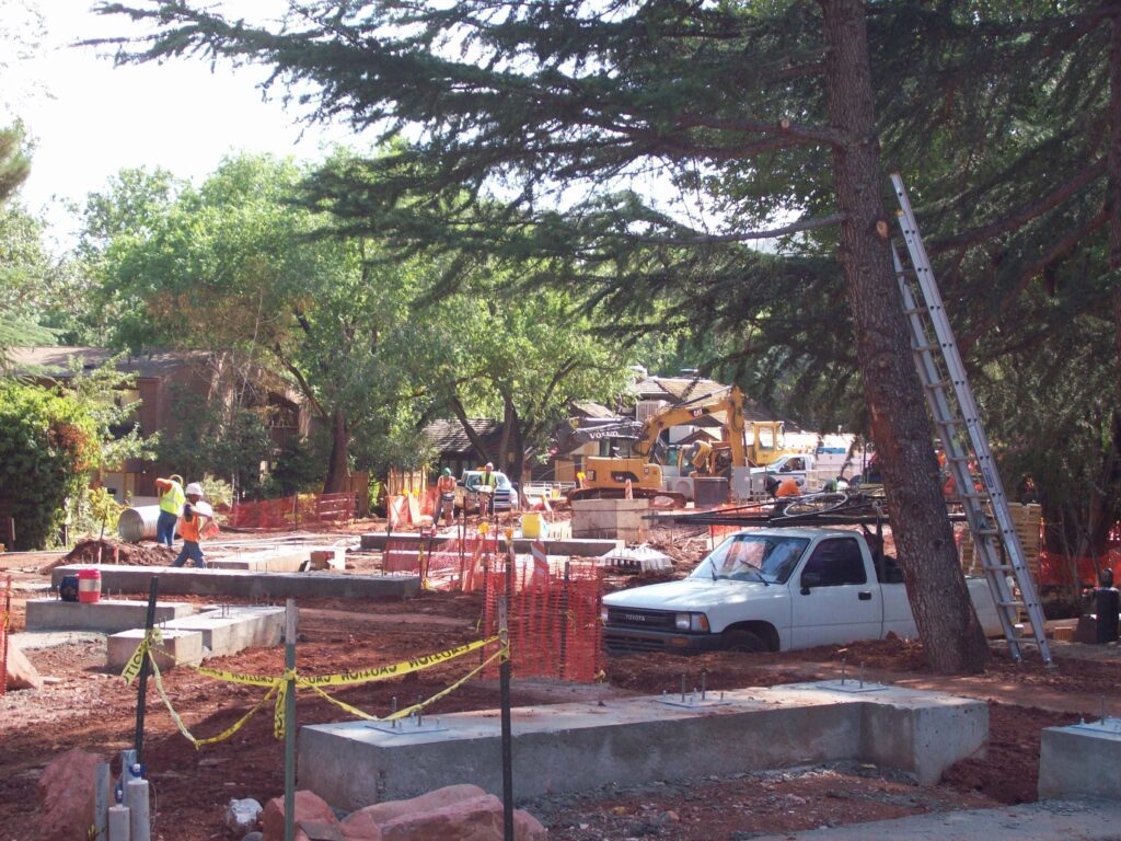Construction zone with workers and trucks between trees