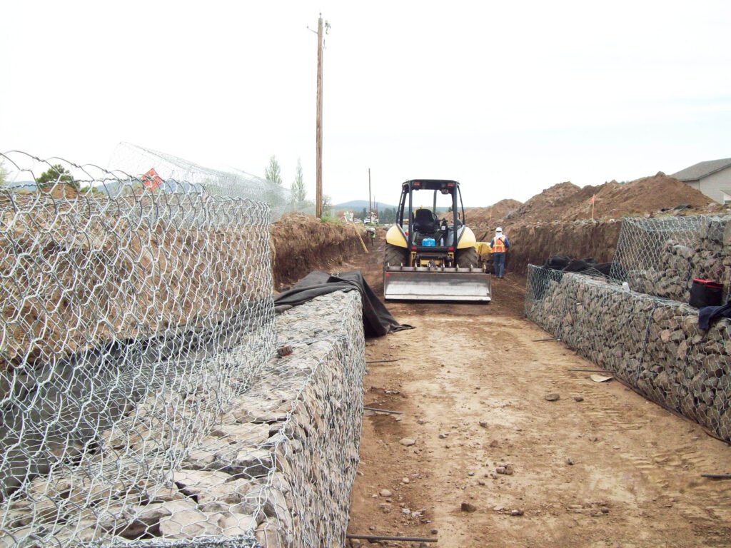 Front loader in a partially completed rock lined drainage channel